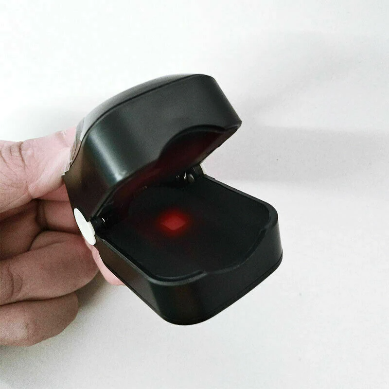 Black Fitlybuy finger pulse oximeter held open with a glowing red sensor light visible against a white background.