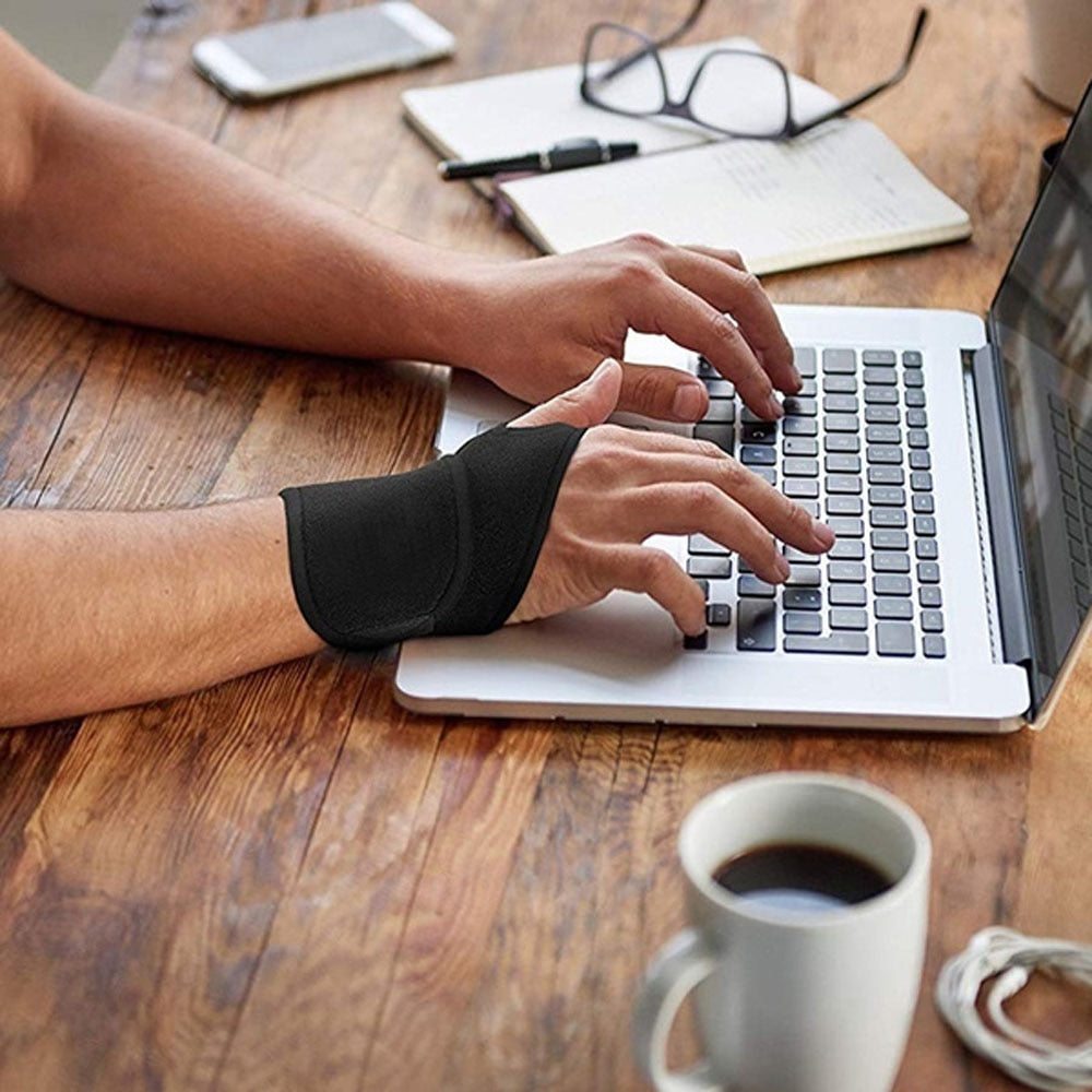 Black Fitlybuy carpal tunnel brace worn on hand while typing on a laptop at a desk.