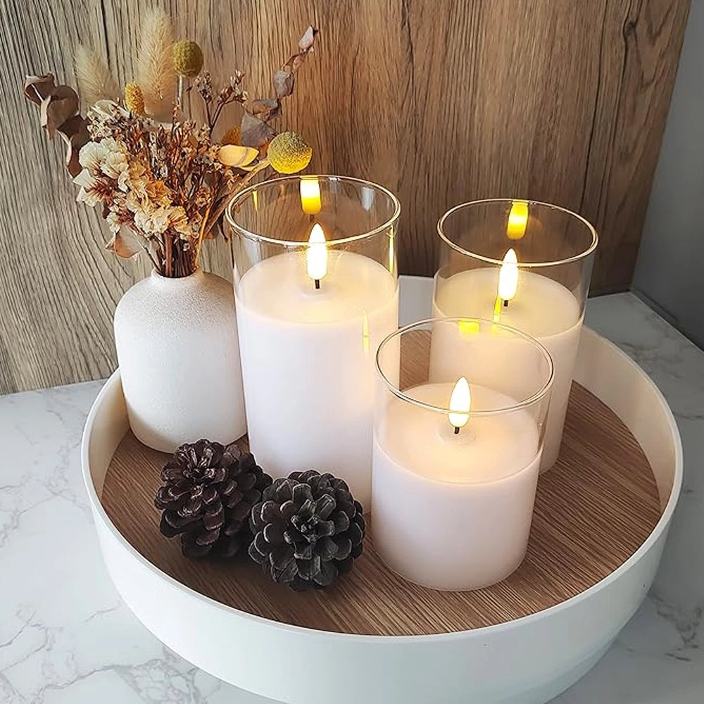Fitlybuy AuraFlame LED candles in glass holders on a tray with a dried flower vase and pinecones.
