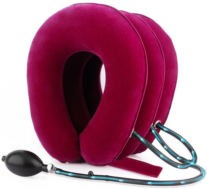 Magenta velvet cervical traction neck support device with inflatable air pump and tube on a white background.