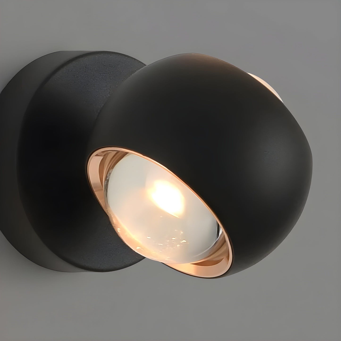 Fitlybuy ModernEdge rotating wall light with a matte black spherical design, rose gold trim, and glowing LED bulb.