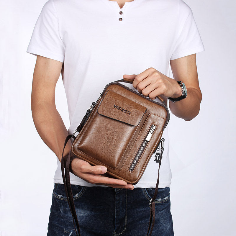 A man in a white shirt holds a luxury brown PU leather shoulder bag with an adjustable crossbody strap and zip pocket.