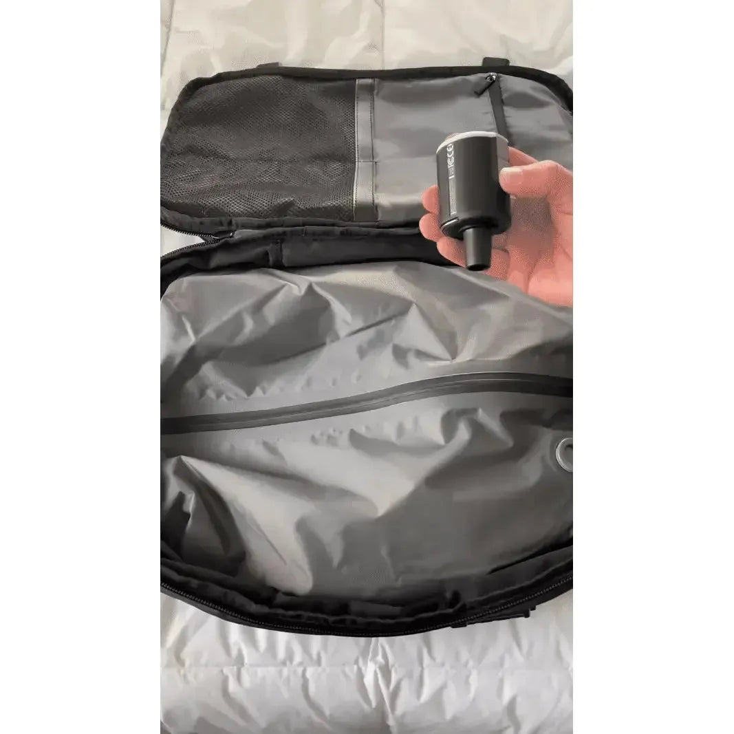 Hand holding a vacuum pump over the interior of an open, black Fitlybuy Lara JetPack travel backpack.
