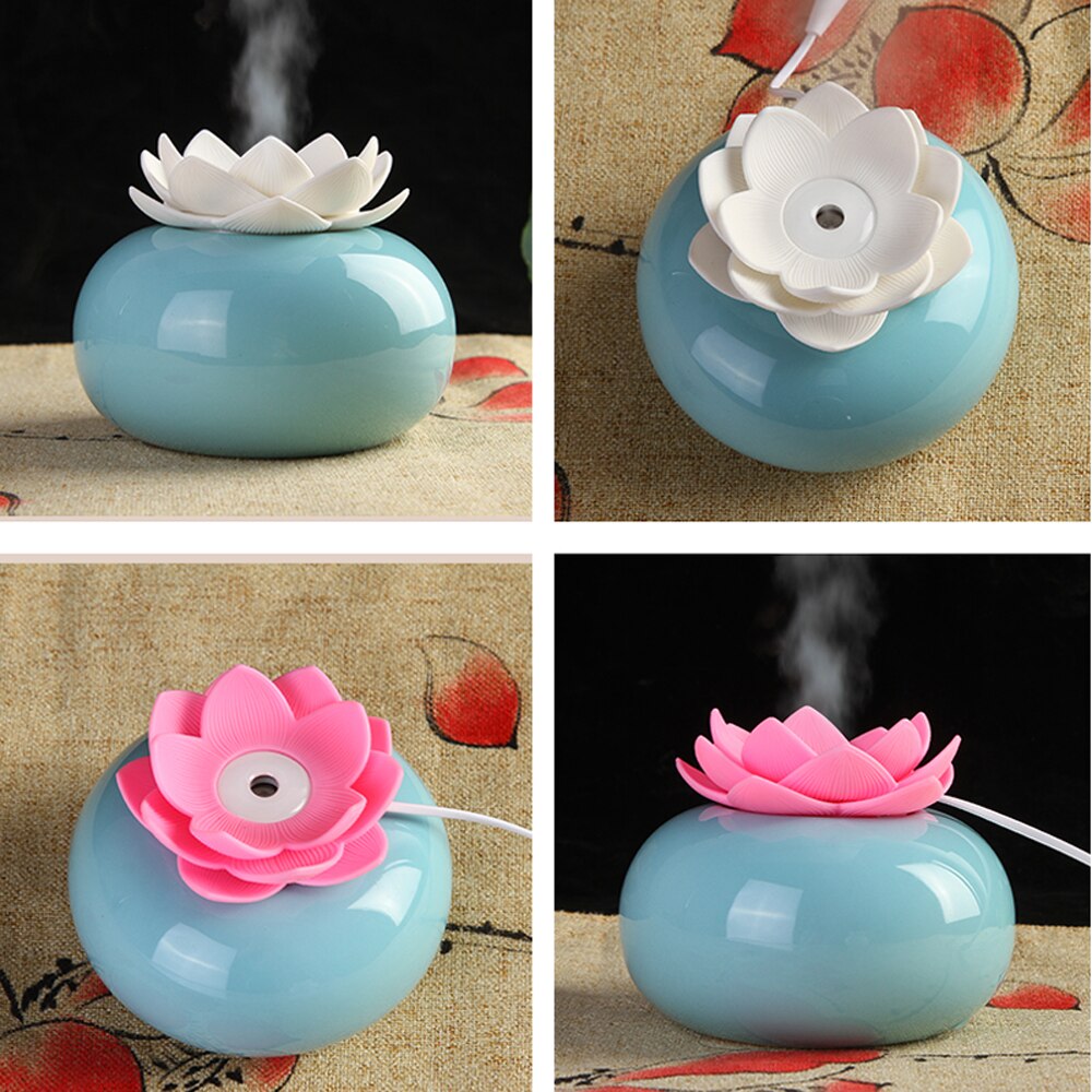Blue ceramic lotus aroma diffuser with white or pink lotus topper, emitting ultrasonic mist on patterned fabric.