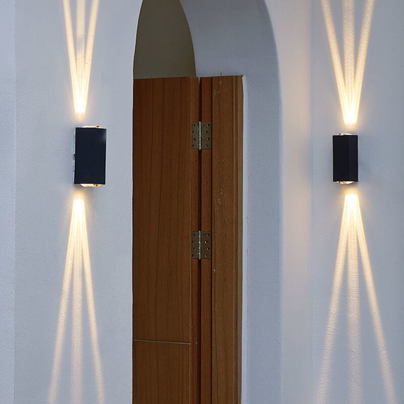 Two black rectangular LED wall lights mounted on a white exterior wall, casting warm beams of light up and down.