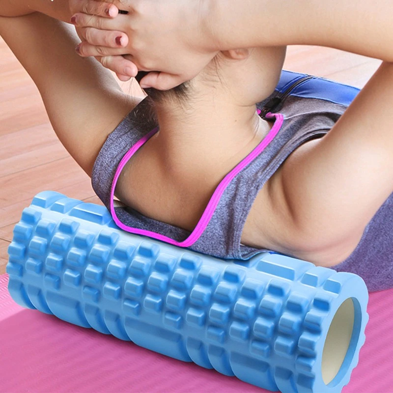 Person using a textured, light blue Fitlybuy Yoga Foam Roller for back massage on a pink yoga mat.
