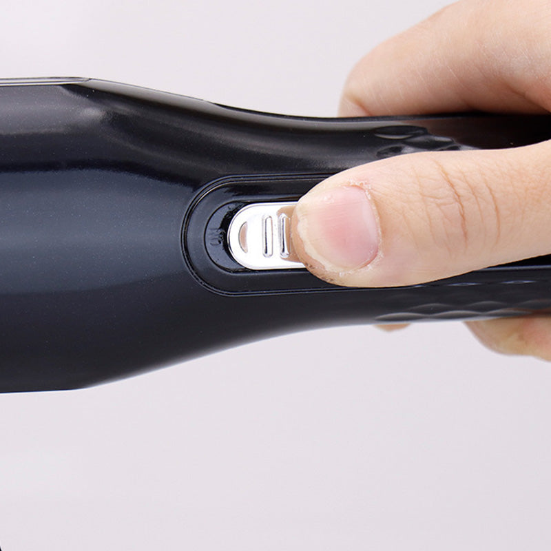Hand holding a sleek, black Fitlybuy automatic split-end hair trimmer, finger pressing the silver power switch.