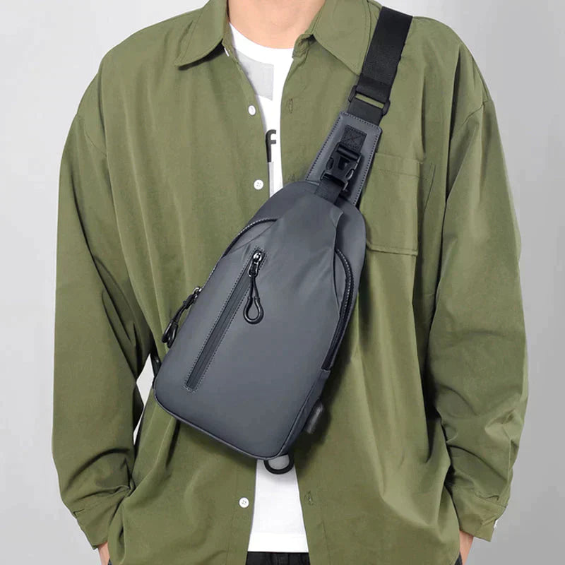 Grey Fitlybuy waterproof anti-theft crossbody bag with SecureLock strap, worn by a man in an olive green shirt.
