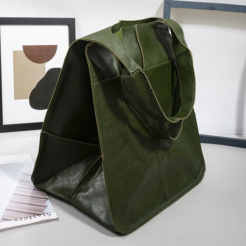 Fitlybuy oversized green leather weekender bag with dual straps, posed on a desk with framed art and a magazine.