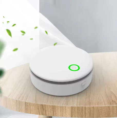 White, circular Fitlybuy FreshAir ozone purifier with a glowing green button, sitting on a wooden table.