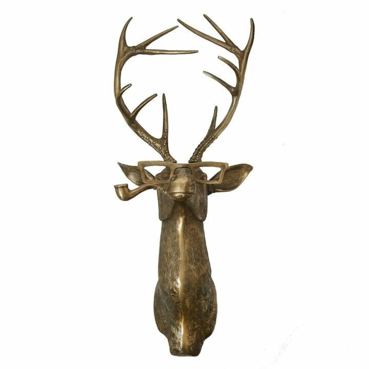 Bronze-colored deer head wall decor wearing glasses and holding a pipe in its mouth, isolated on a white background.