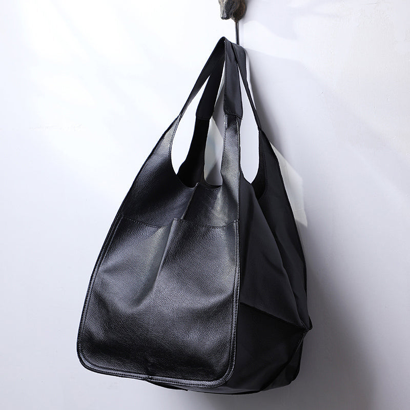 Fitlybuy oversized black leather weekender tote bag with wide shoulder straps, hanging on a wall hook.