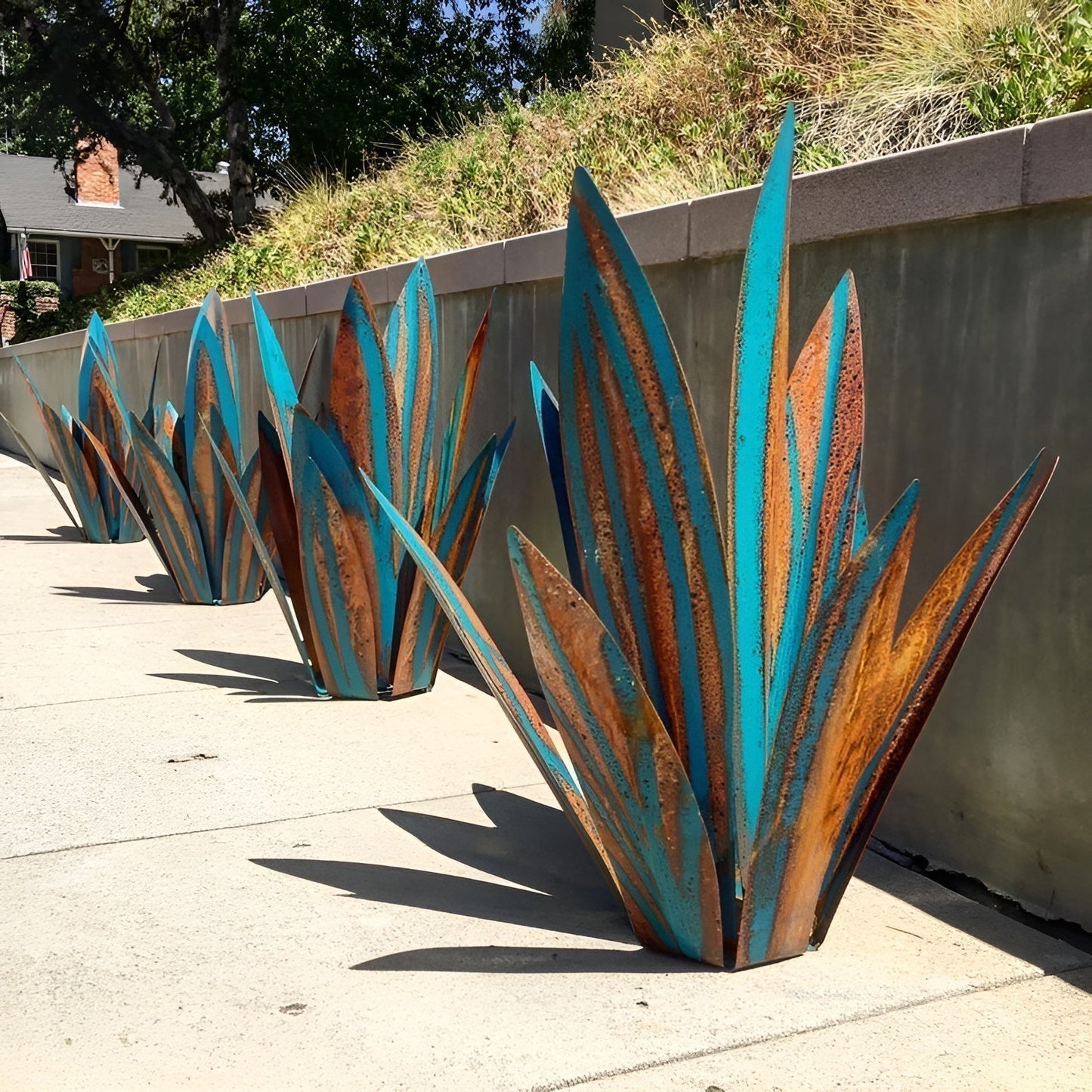 Fitlybuy rust-proof metal agave garden sculptures with a blue and rustic brown finish, displayed on a concrete sidewalk.