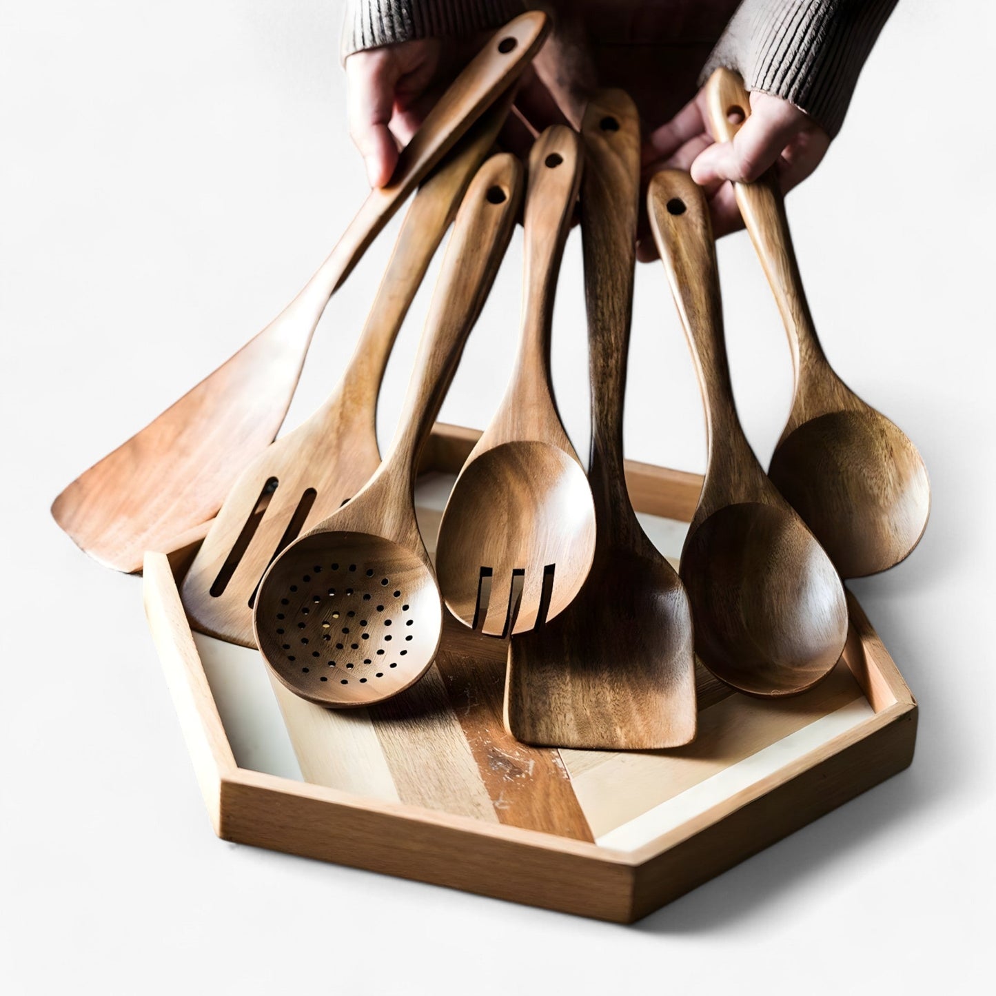 Person holding a 9-piece premium teak wood kitchen utensil set with hanging loops, displayed in a wooden tray.