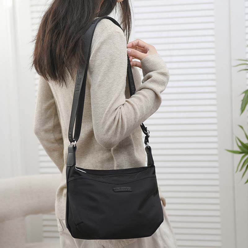 Woman wearing a black Fitlybuy Joanna waterproof anti-theft shoulder bag as a secure travel crossbody.