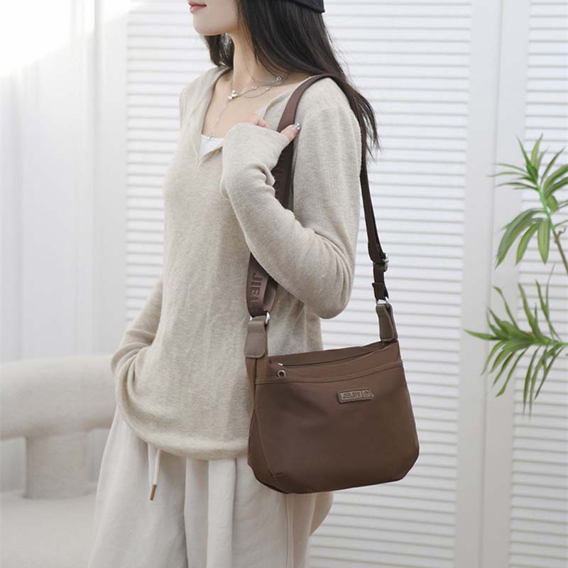Woman wearing a brown Fitlybuy Joanna waterproof anti-theft crossbody bag with adjustable branded shoulder strap.