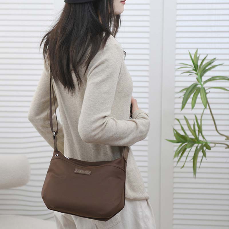 Woman wearing a brown Fitlybuy Joanna waterproof anti-theft crossbody shoulder bag with a secure, minimalist design.