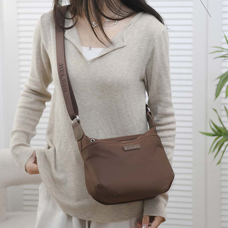 Woman wearing a brown Fitlybuy Joanna waterproof crossbody bag with an adjustable logo shoulder strap.