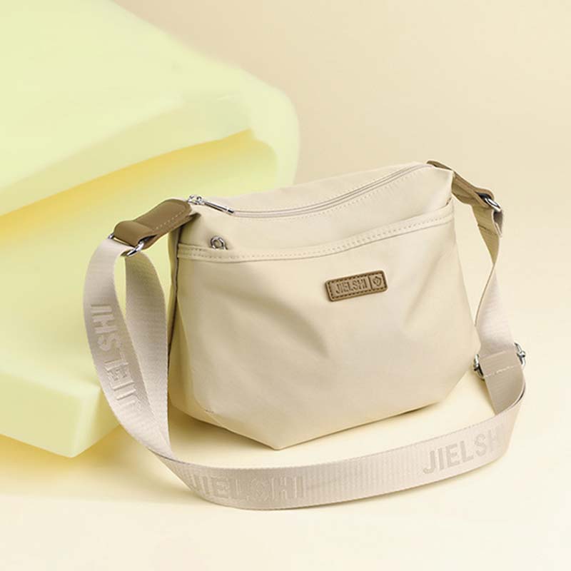 Beige Fitlybuy Joanna waterproof crossbody bag with a branded logo patch and an adjustable logo-patterned shoulder strap.