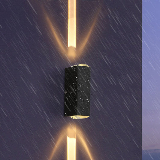 Waterproof black rectangular LED outdoor wall light emitting upward and downward beams on a wet exterior wall.