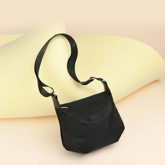 Fitlybuy Joanna black waterproof anti-theft crossbody bag with an adjustable branded shoulder strap on a yellow backdrop.