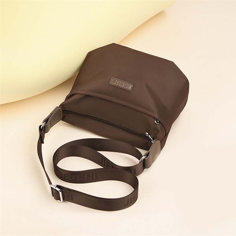 Brown waterproof crossbody shoulder bag with secure zippered pockets and branded adjustable strap on a neutral background.