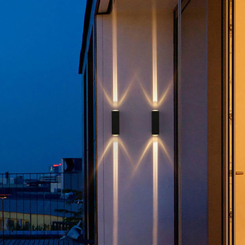 Two black rectangular waterproof LED wall lights illuminate a balcony wall with upward and downward beams at night.