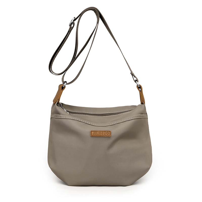 Taupe anti-theft crossbody bag with zip closure, adjustable strap, tan accents, and Jielshi brand tag on white background.
