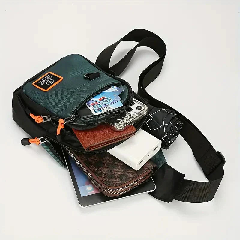 Dark green and black waterproof Fitlybuy crossbody bag filled with a tablet, wallet, power bank, and cards.