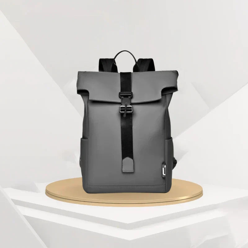 Grey Fitlybuy BergTrek waterproof roll-top backpack with black straps and buckle on a pedestal display.