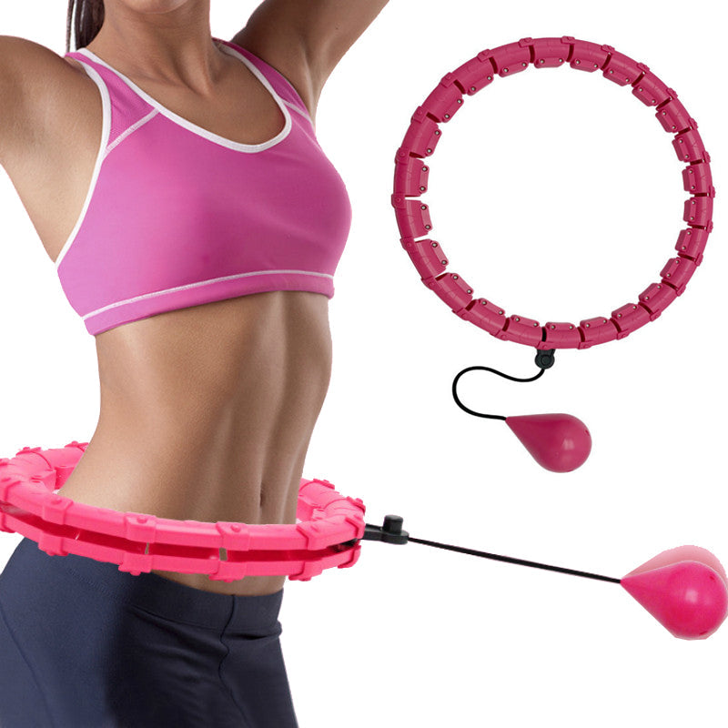 A woman wearing a pink sports bra uses a pink Fitlybuy smart hula hoop with an adjustable weighted gravity ball.