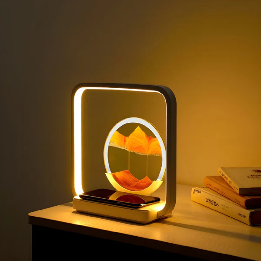 Fitlybuy SandAura square LED lamp with internal circular orange sand art, on a table beside books and a phone.
