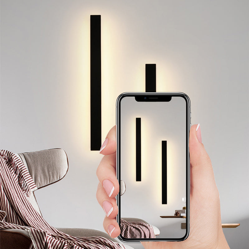 Fitlybuy modern black minimalist LED wall light with warm glowing light, viewed on a smartphone screen in a living room.