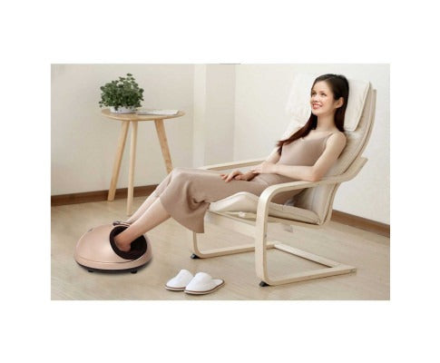 A woman relaxes in a chair using a gold Fitlybuy 3D Shiatsu heat foot massager with black interior accents.