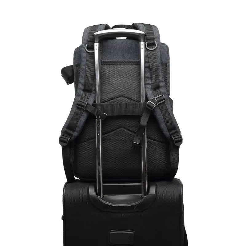 Dark gray Fitlybuy Beckett waterproof camera backpack attached to the handle of a black rolling luggage suitcase.