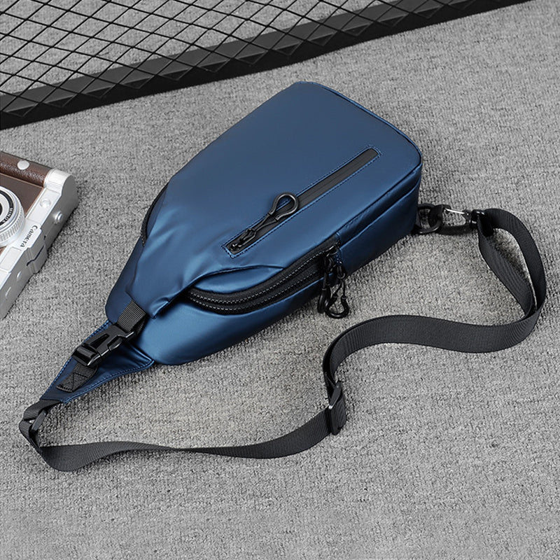 Blue Fitlybuy waterproof anti-theft crossbody bag with secure lock zippers, adjustable strap, on a gray surface.