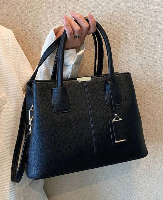 Black Fitlybuy PU leather handbag with dual handles, detachable strap, and gold-tone hardware, held by a hand.
