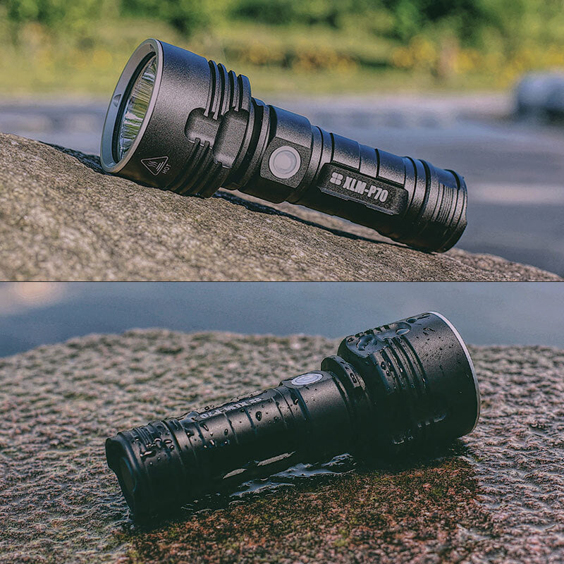 Black, rechargeable high-power LED flashlight on a wet stone, showing waterproof design and durable metallic finish.