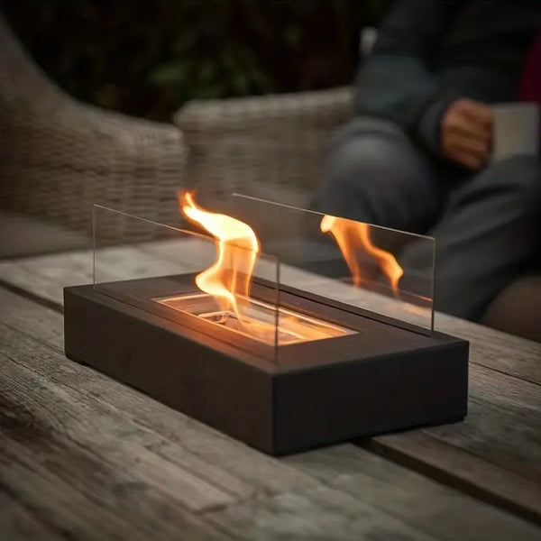 Fitlybuy black rectangular tabletop bio-ethanol fireplace with glass guards, featuring a smokeless flame on a patio table.