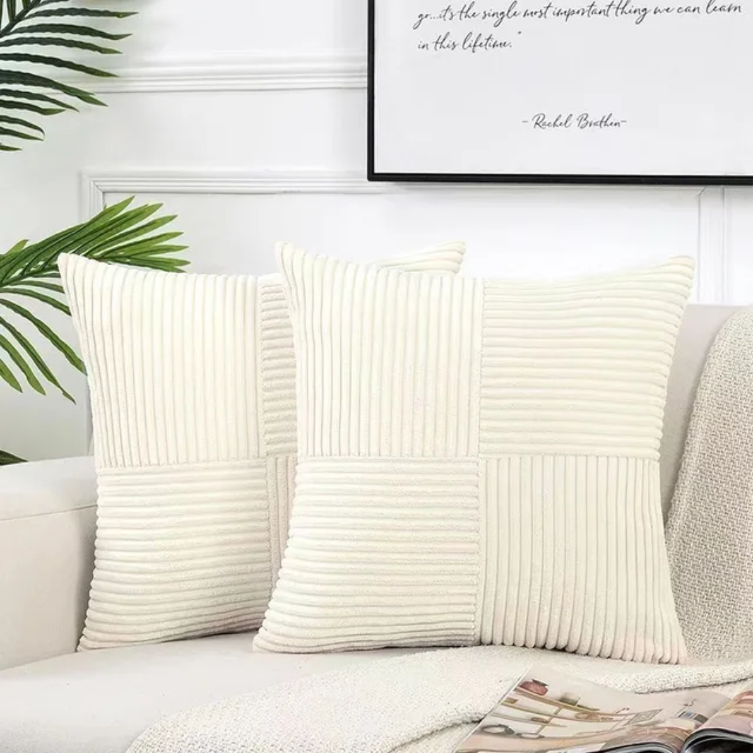 Two ivory, square corduroy throw pillows with a checkered ribbed pattern, displayed on a sofa in a stylish room.
