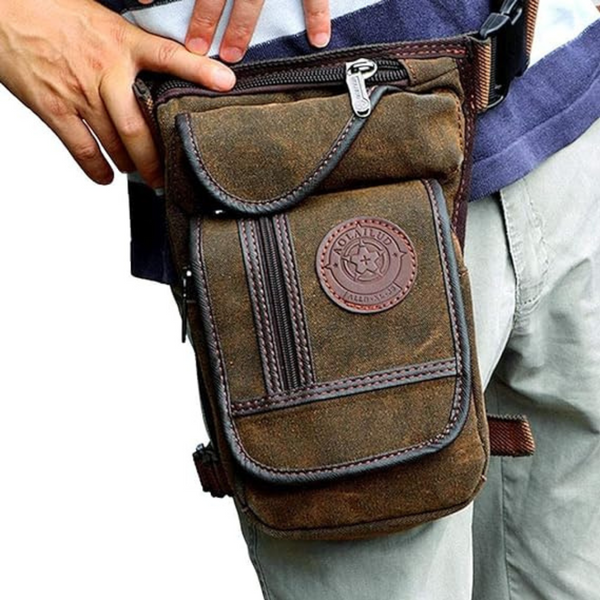 Brown waterproof canvas motorcycle leg bag with zipper pockets, adjustable straps, and a circular patch on the thigh.