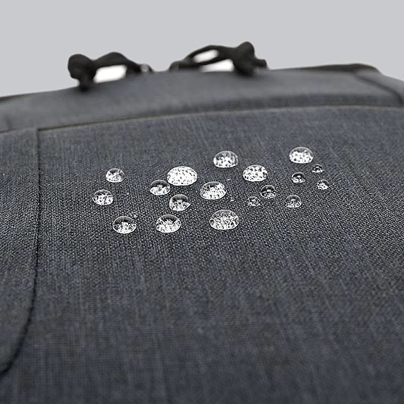 Close-up of gray Fitlybuy Beckett waterproof camera backpack fabric showing water beads on its protective surface.