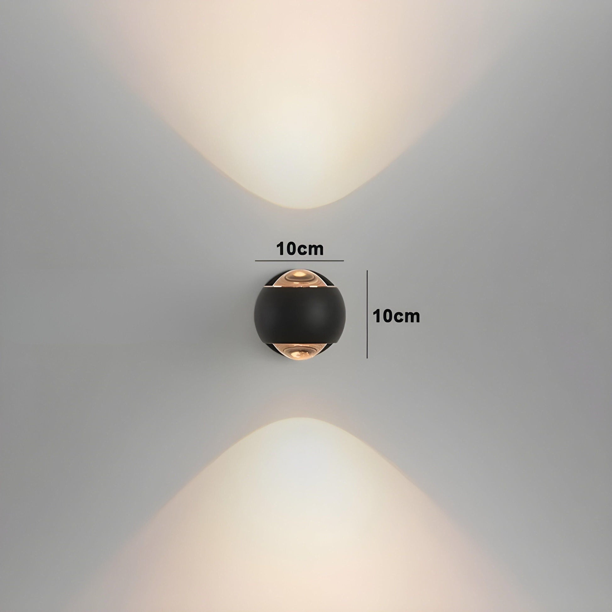 ModernEdge round black LED wall light emitting upward and downward beams. 10x10cm size marked on a neutral wall.