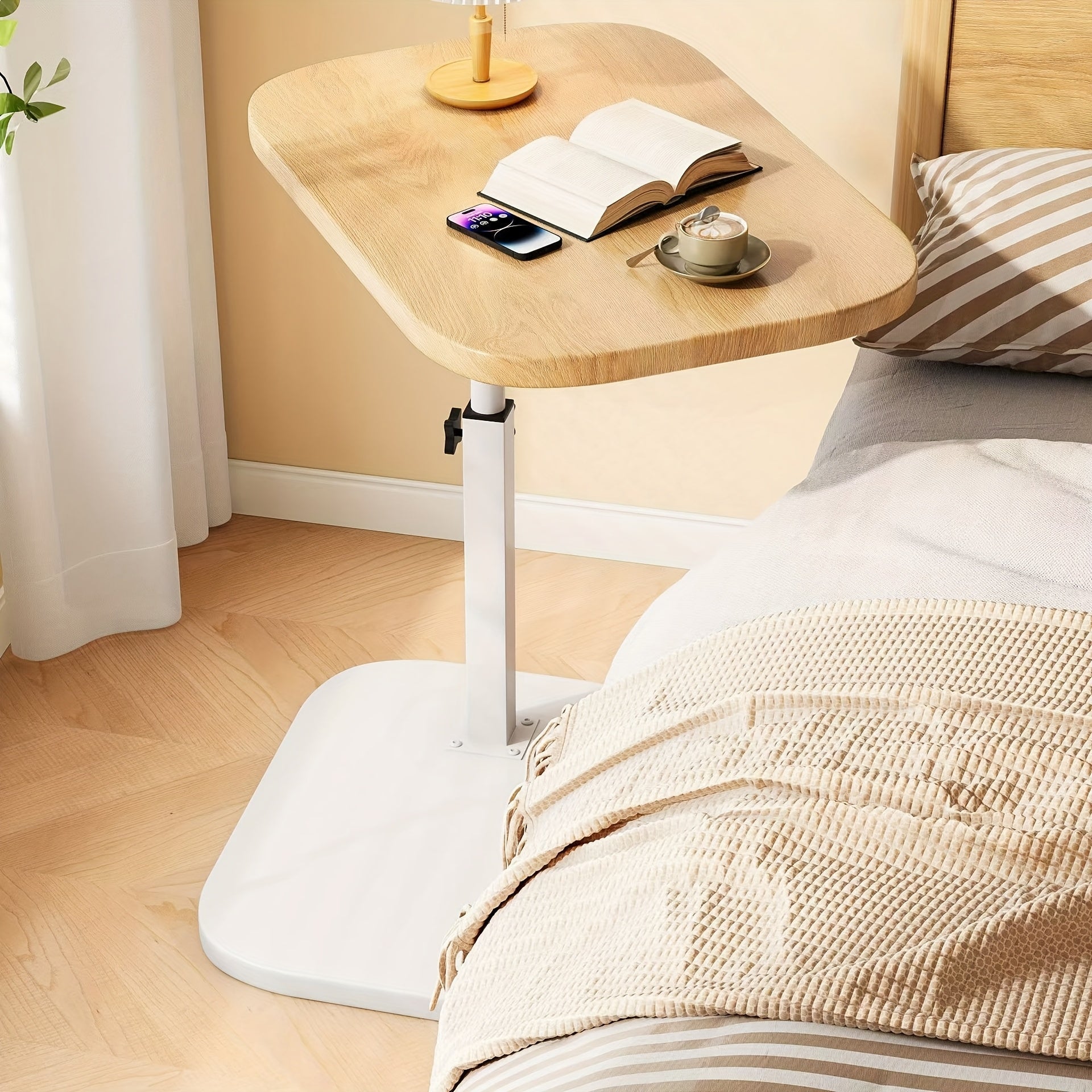 Fitlybuy adjustable wooden-top side table with white base positioned next to a bed, holding a book, phone, and coffee.