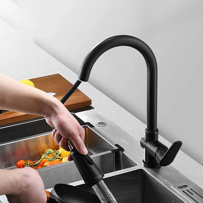 Fitlybuy Velvra matte black pull-out kitchen tap with single lever, shown in use over a stainless steel sink.