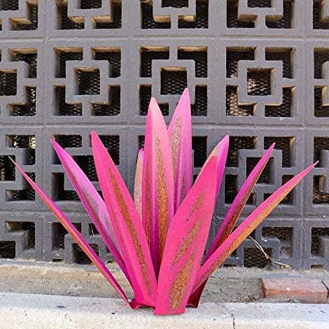 Fitlybuy handcrafted pink and rustic metal agave sculpture placed on a concrete ledge in front of a geometric wall.