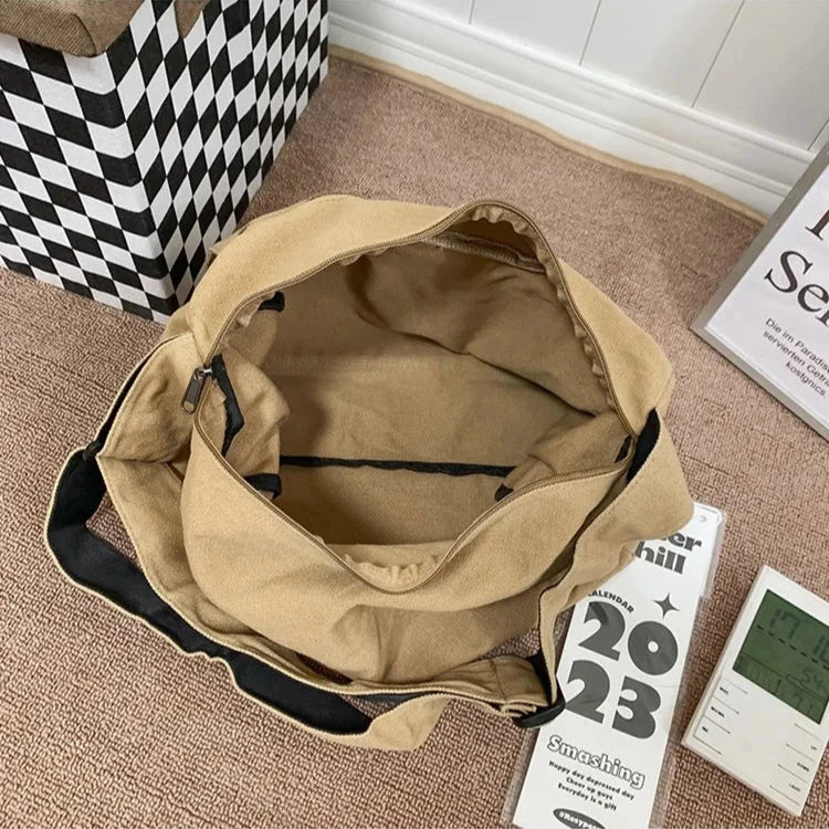 Open tan canvas Fitlybuy CrossStream sling bag with a zippered main compartment and black shoulder strap.