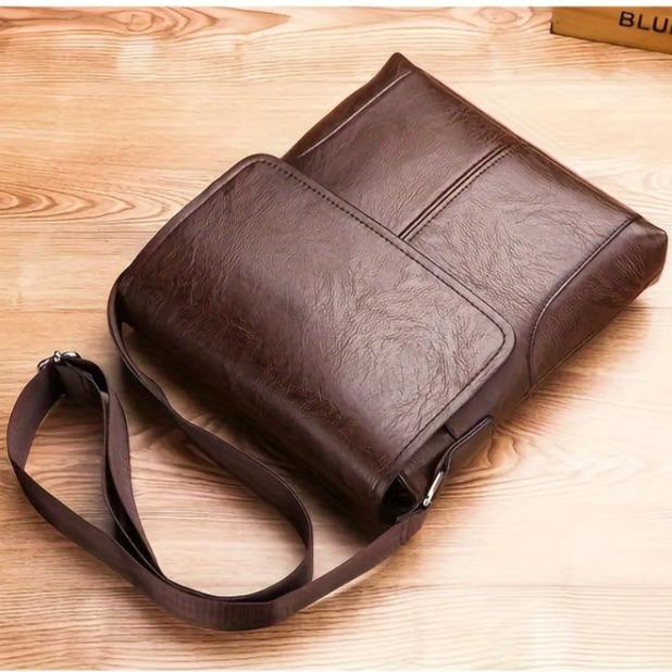 Brown vintage-style PU leather shoulder bag with a flap closure and adjustable strap, set on a wooden background.