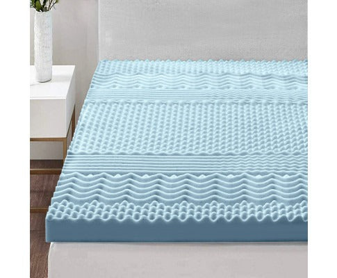 Light blue Fitlybuy 7-zone memory foam mattress topper with textured surface, displayed on a bed in a bedroom.