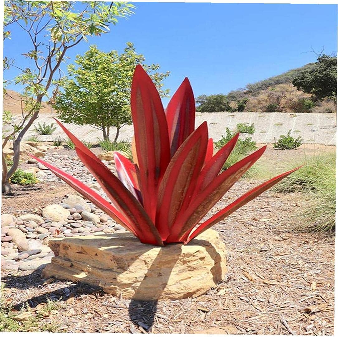 Red handcrafted metal agave garden sculpture on a rock base, featuring a weather-resistant finish in a desert landscape.